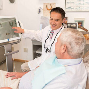 our-doctor-showing-dentures-to-a-old-man-patient at Eleven Eleven Dental